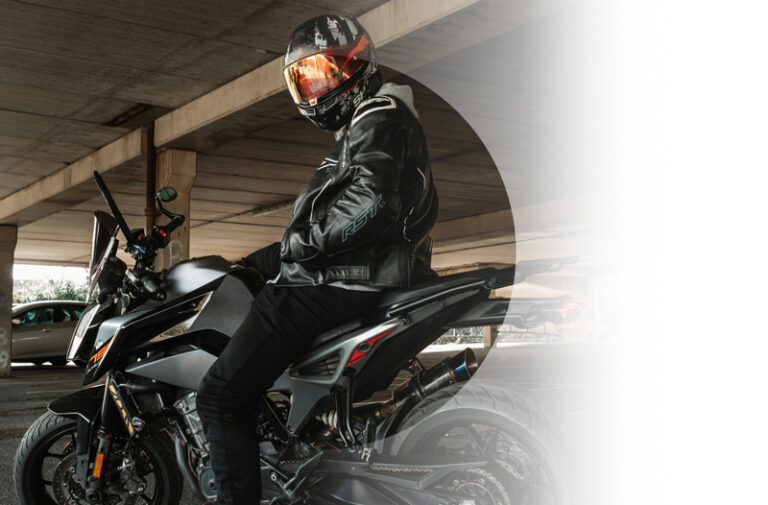 A person in leather jacket on a motorcycle inside a parking garage.