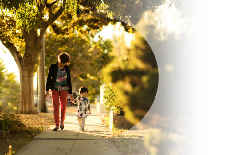 Health Insurance example. Img: A grandmother and child walking down a tree-lined walkway.