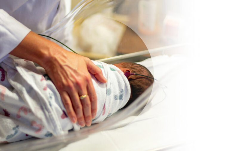 Supplemental Insurance example. Img: Close up of a newborn baby swaddled with a persons hand resting on them.